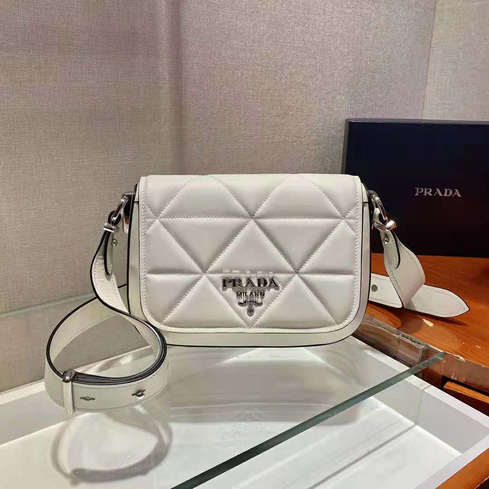 Close-up of silver Prada logo hardware on white leather bag