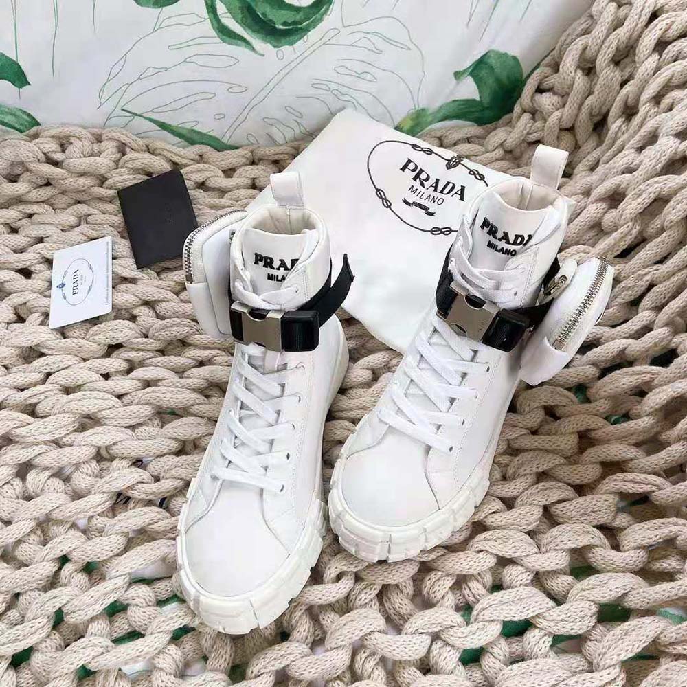 Close-up of Prada logo hardware on white Re-Nylon high-top sneakers