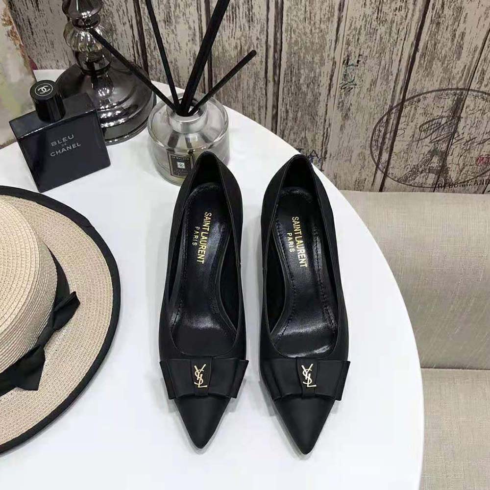 Close-up of signature gold YSL logo hardware on black leather pumps