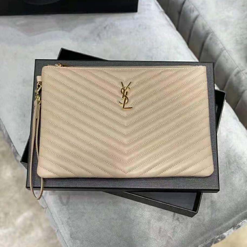 Close-up of gold-tone YSL monogram on beige quilted leather pouch
