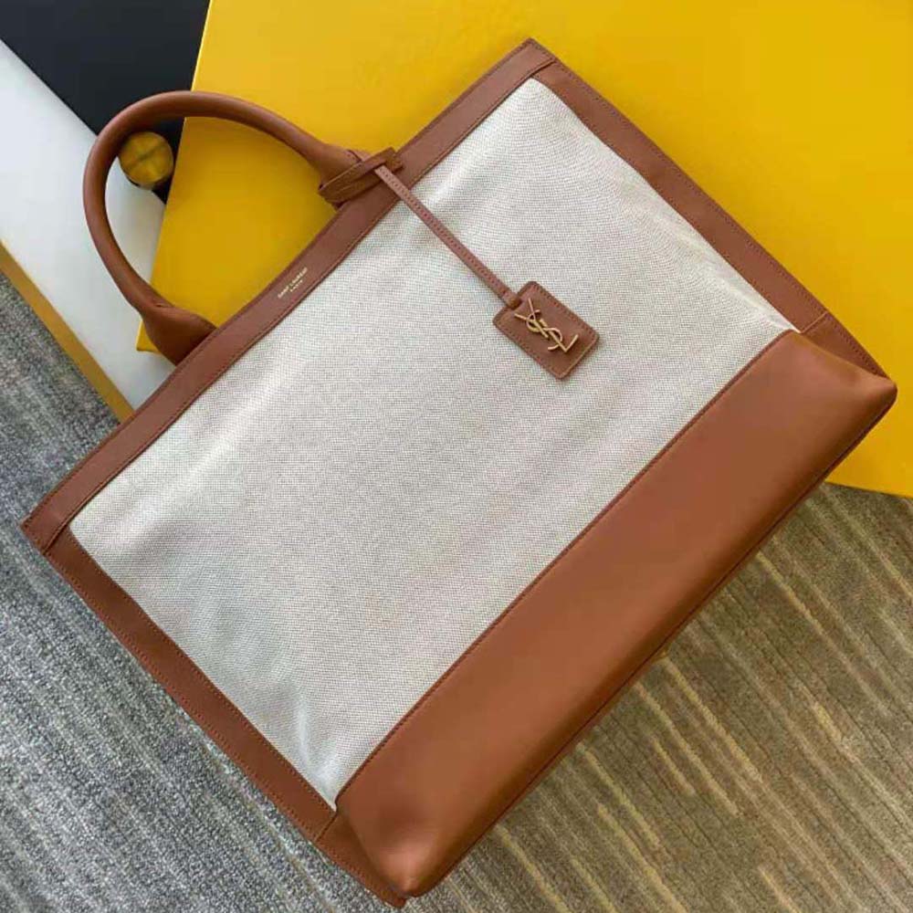 Close-up of gold YSL logo hardware on brown leather handbag