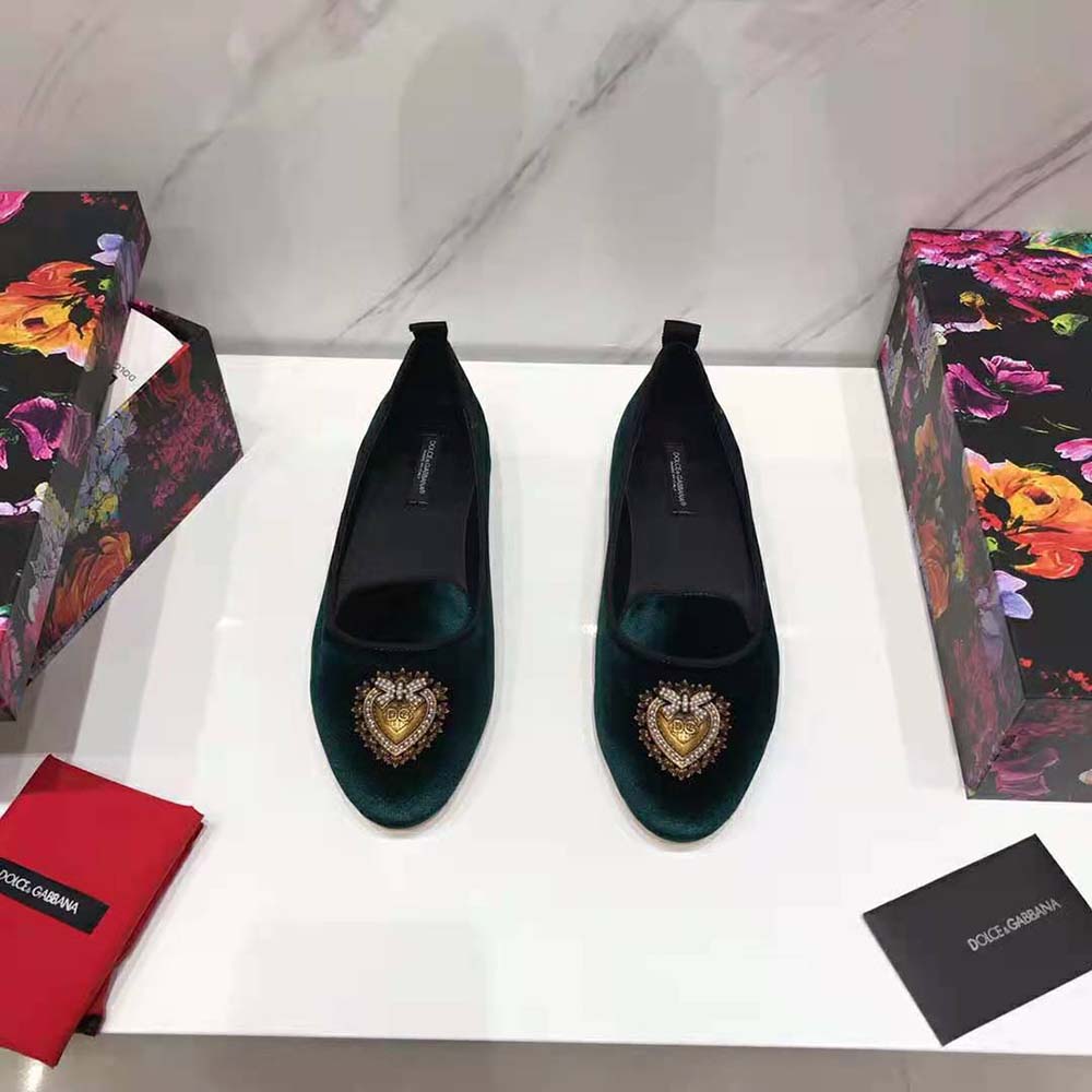 Close-up on gold D&G logo hardware on green velvet slipper