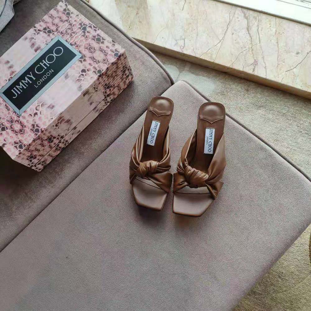 Close-up detail of brown nappa leather and gold hardware on Jimmy Choo mules