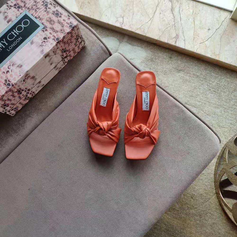 Close-up of orange nappa leather and gold signature on Jimmy Choo mules