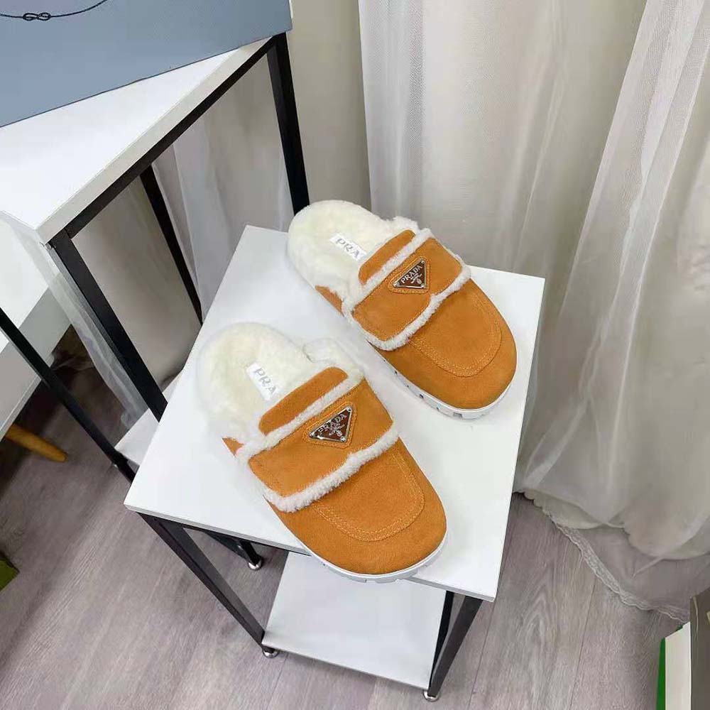 Close-up of enameled metal triangle logo on yellow Prada slippers