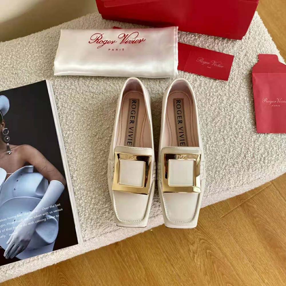Close-up of silver metal buckle detail on white leather loafers by Roger Vivier