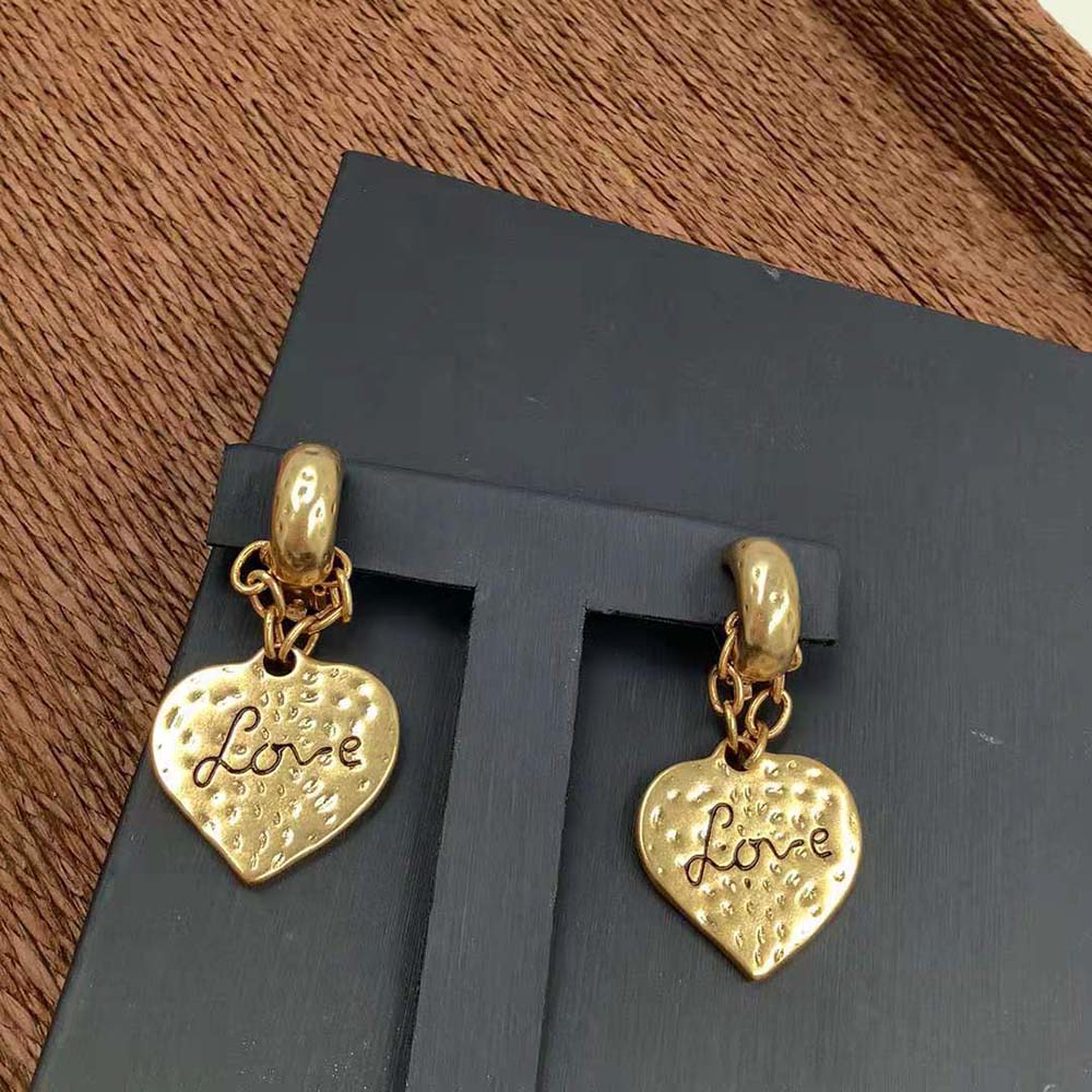 Close-up of heart pendant and YSL logo on earrings