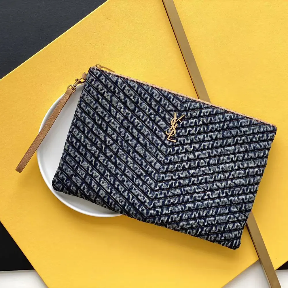 Close-up of gold YSL monogram on quilted vintage denim pouch