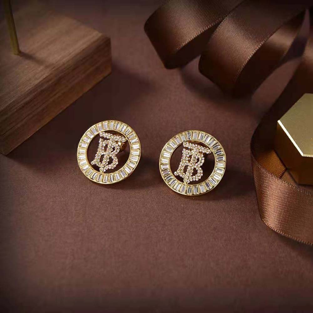 Close-up of Burberry monogram and crystal details on gold-plated earrings