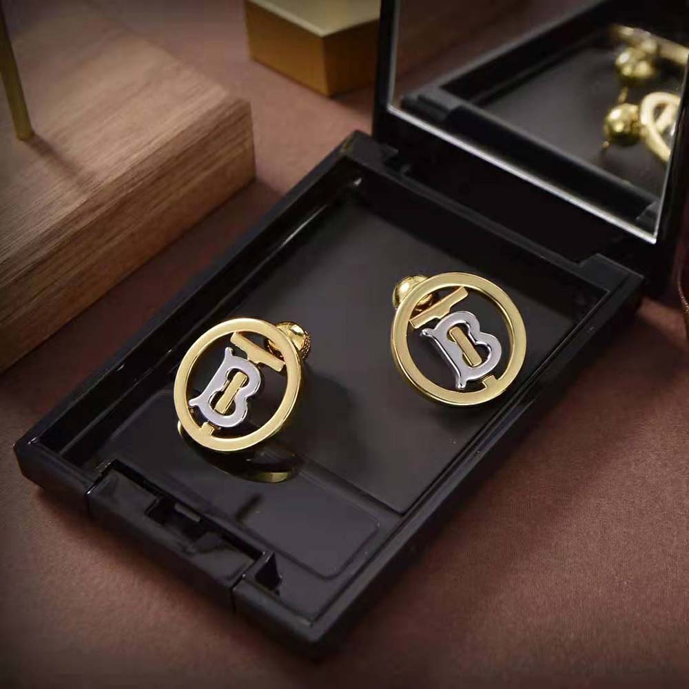 Close-up detail of Burberry monogram on gold and palladium earrings