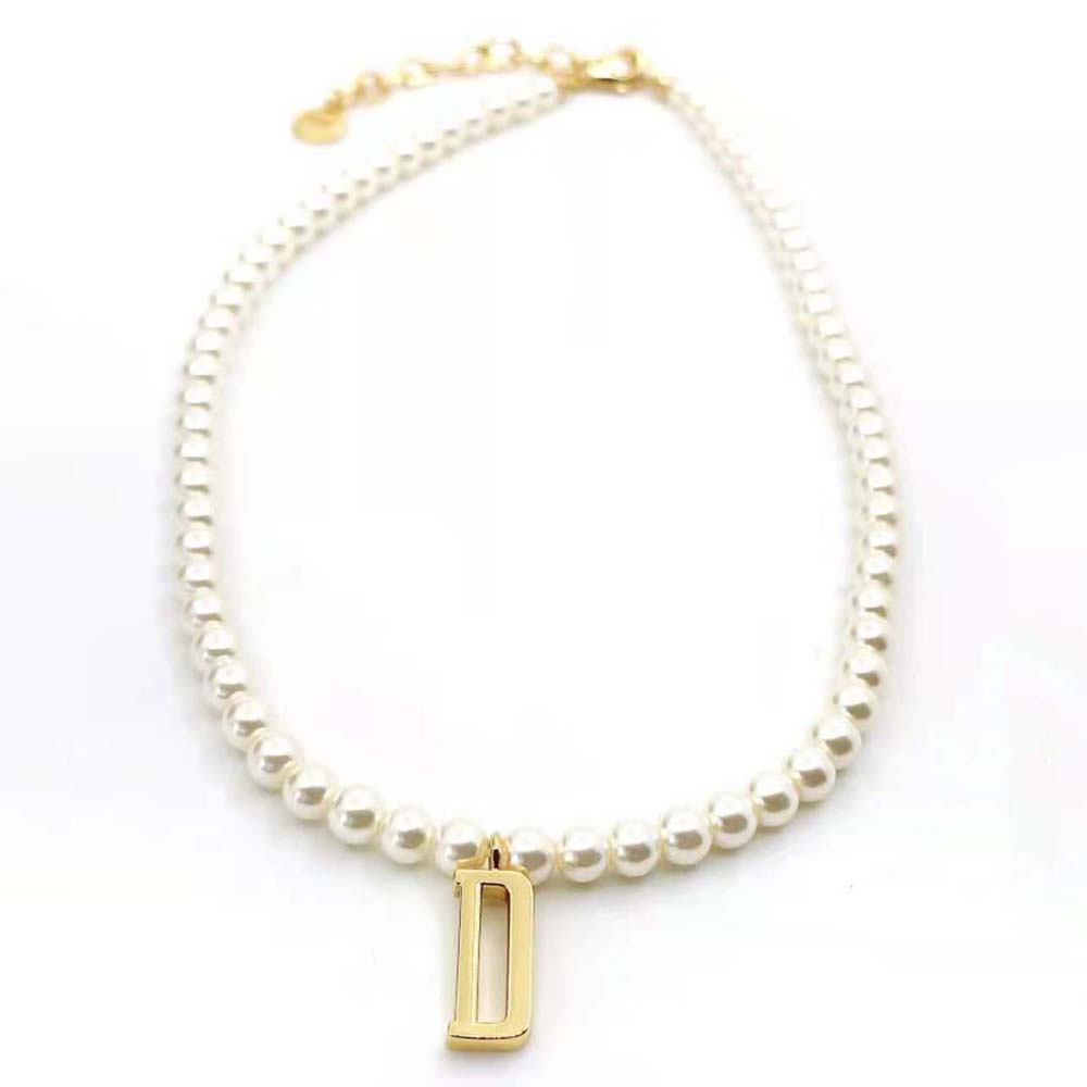 Close-up detail of gold-finish metal and Dior logo on necklace