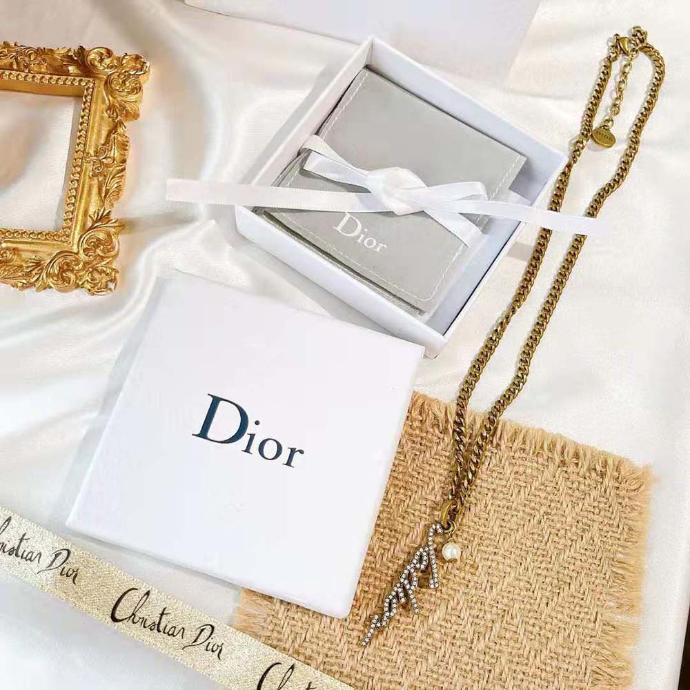 Close-up of resin pearl and gold ‘J adior’ lettering detail on necklace
