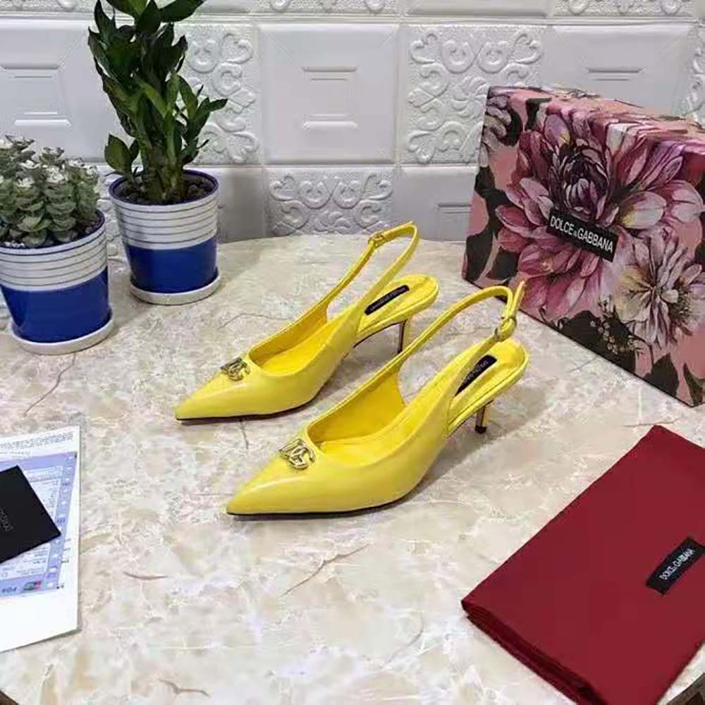Close-up of gold DG logo hardware on yellow patent leather slingback