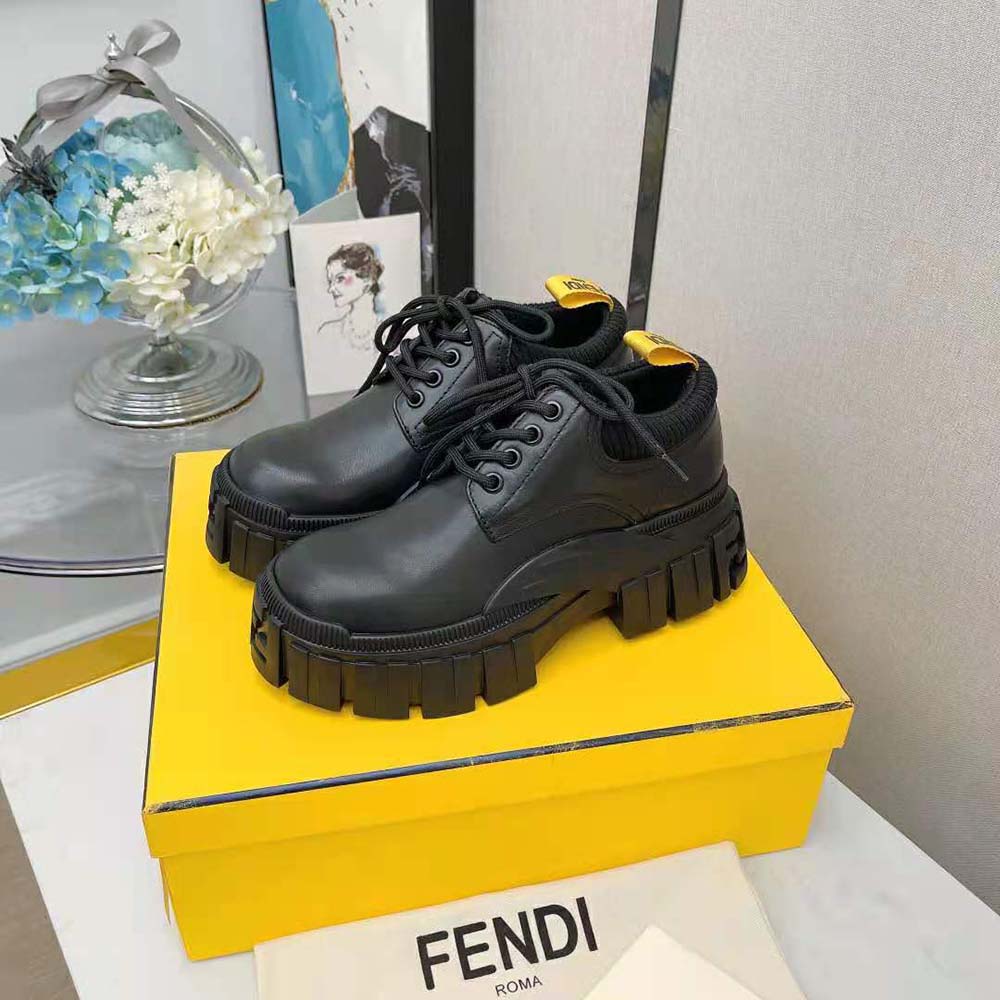 Close-up on embossed Fendi logo hardware on black leather lace-ups
