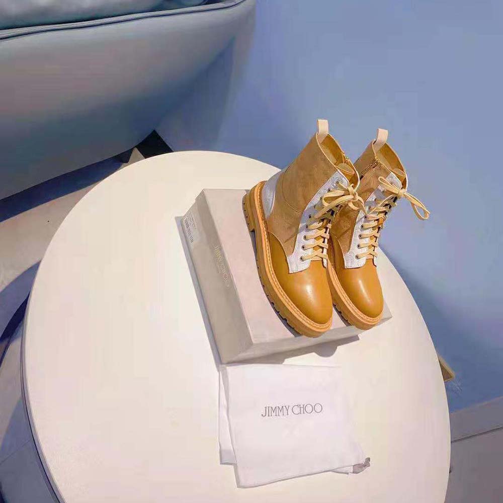 Close-up of gold JC monogram hardware on caramel combat boots