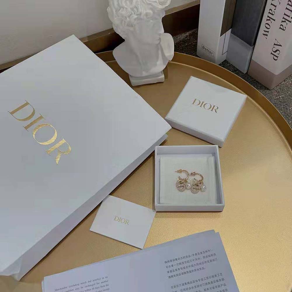 Close-up detail of gold-finish metal and CD hardware on Dior earrings