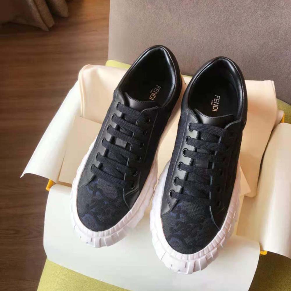Close-up detail of Fendi logo hardware on black fabric sneaker