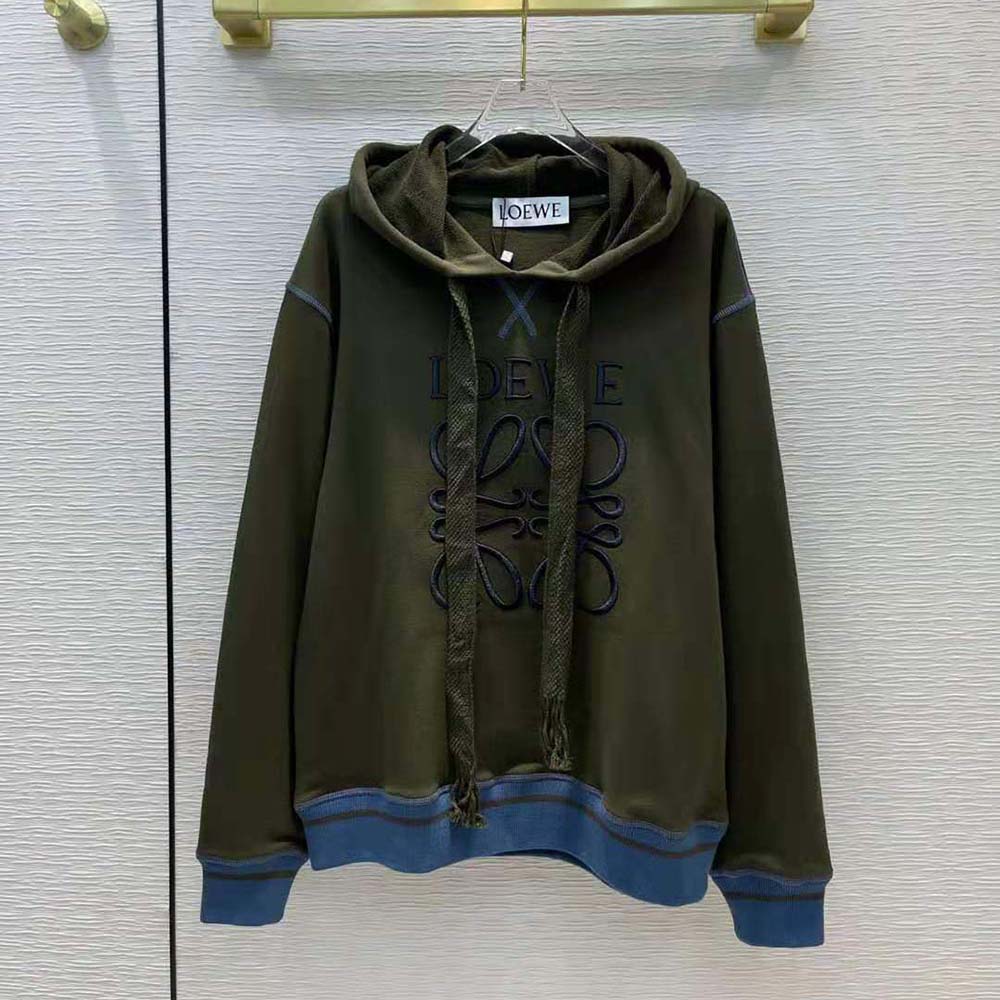 Close-up of embroidered Loewe Anagram on green hoodie