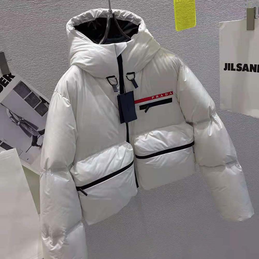 Close-up of Prada logo hardware on white puffer jacket sleeve