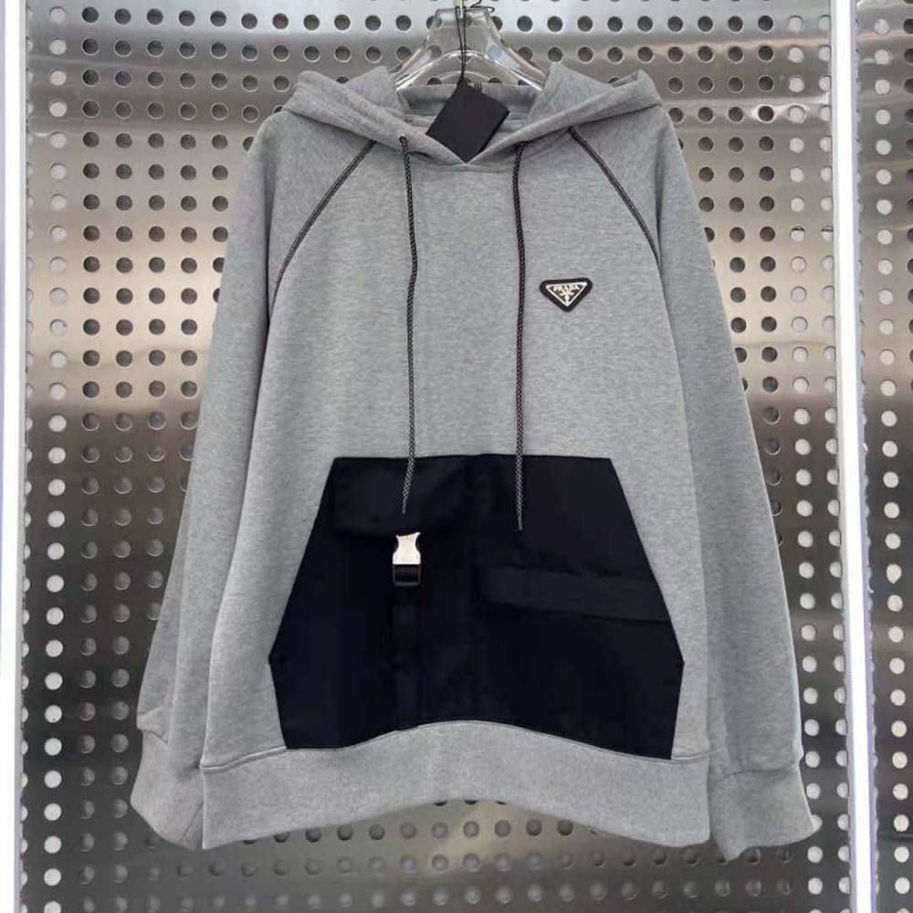 Close-up of Prada logo hardware on silver oversized hoodie with Re-Nylon inserts