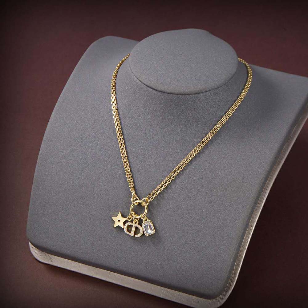 Close-up detail of white crystals and gold ‘CD’ pendant on necklace