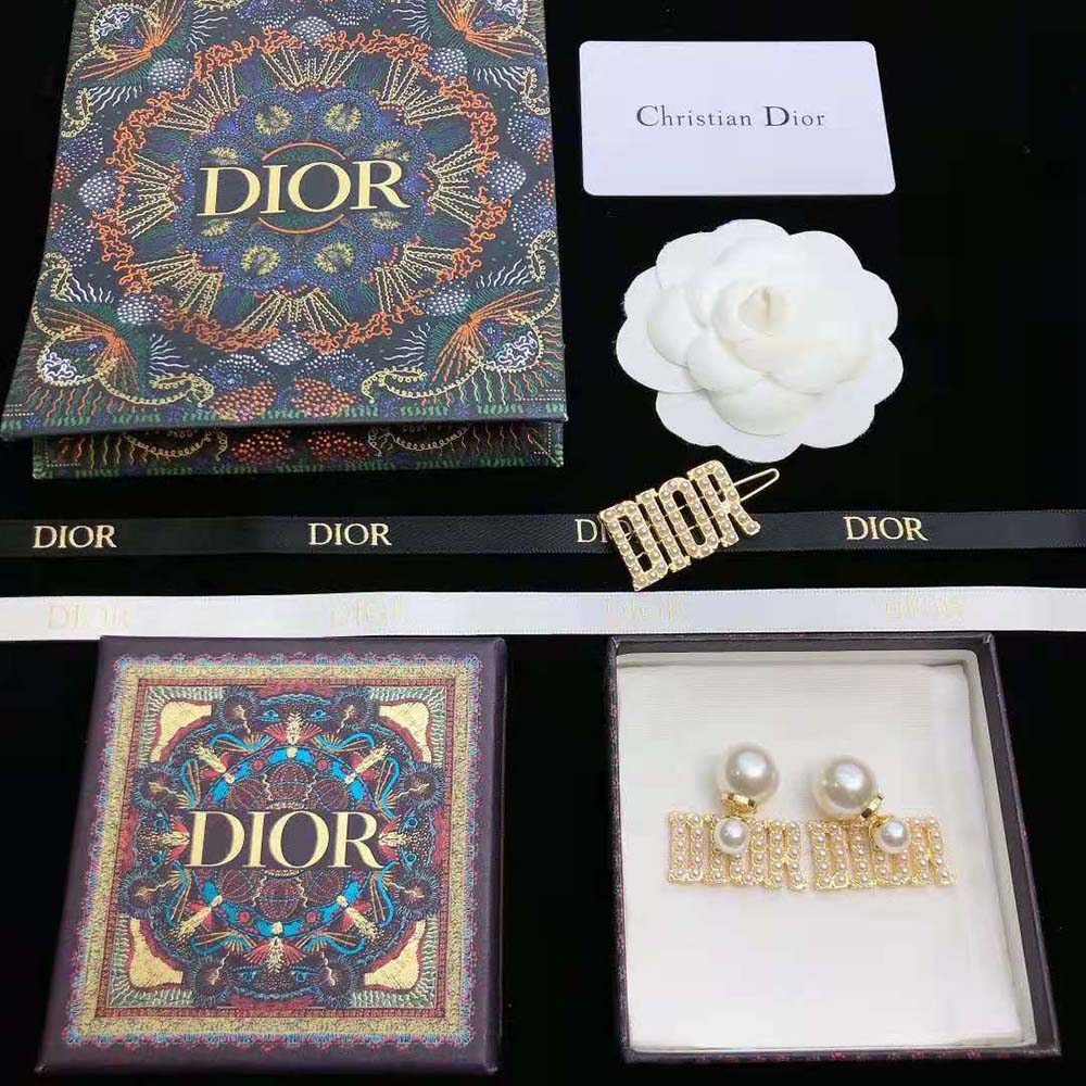 Close-up detail of gold-finish metal and signature pearls Dior earrings