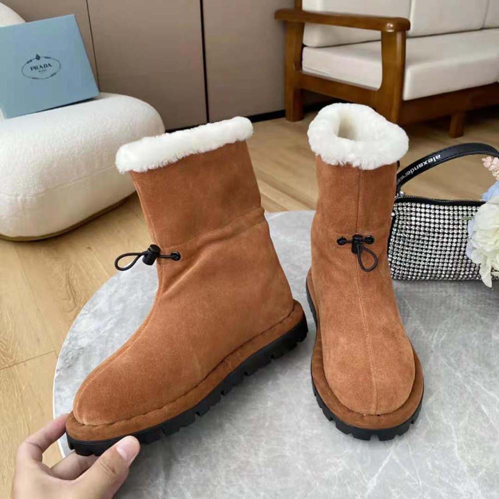 Close-up on Prada triangular logo hardware on shearling booties