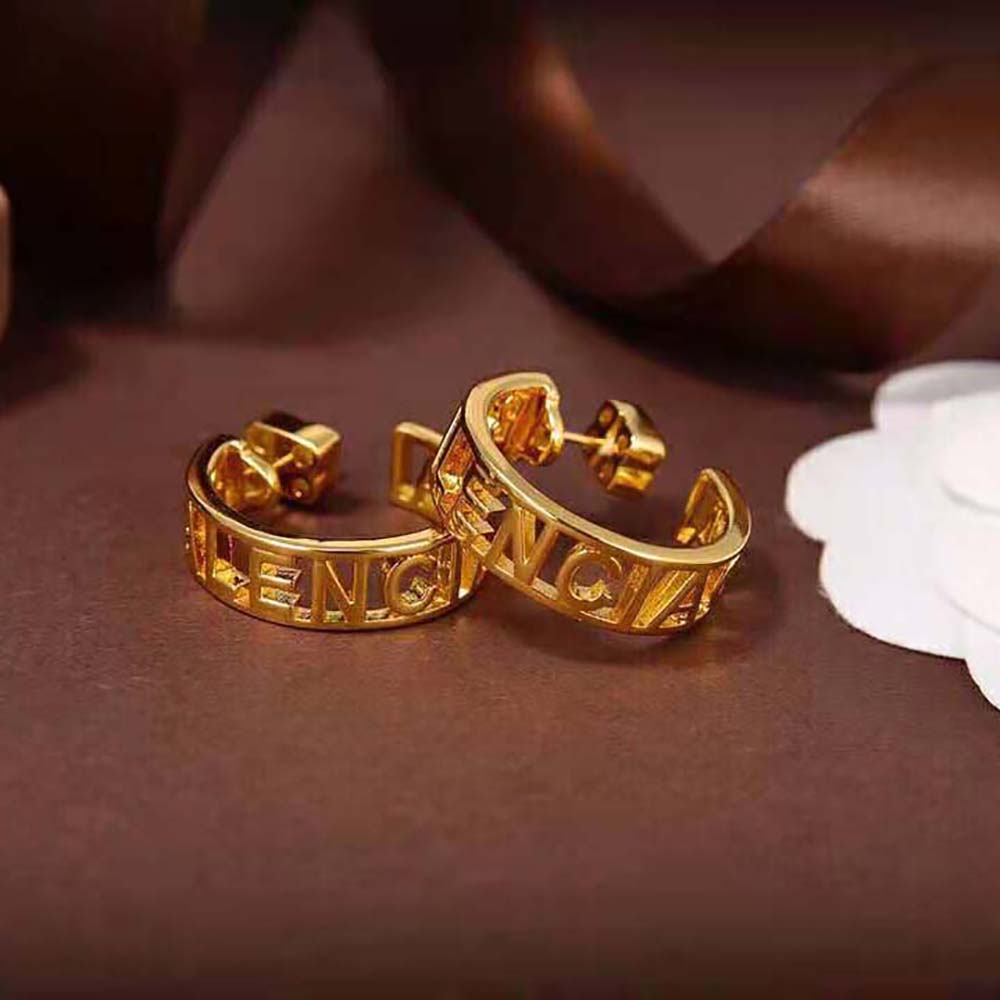 Close-up detail of Balenciaga logo engraving on gold brass earrings