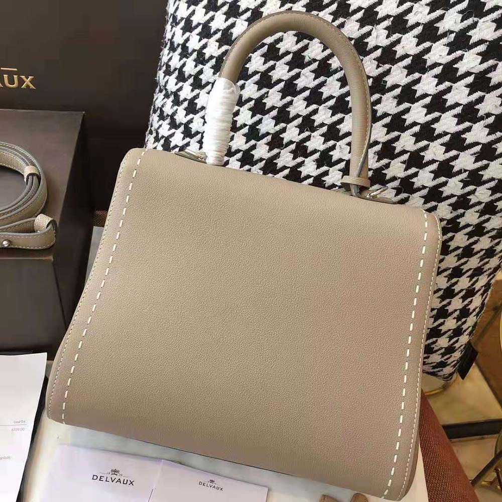Side profile showing compact silhouette of Delvaux Brillant MM Surpique brown bag