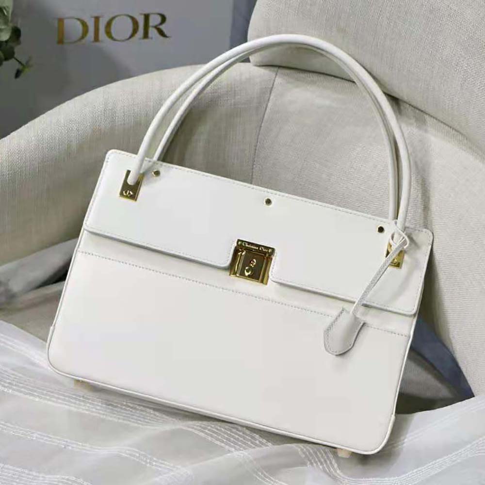 Close-up of gold-tone Dior hardware on white calfskin bag