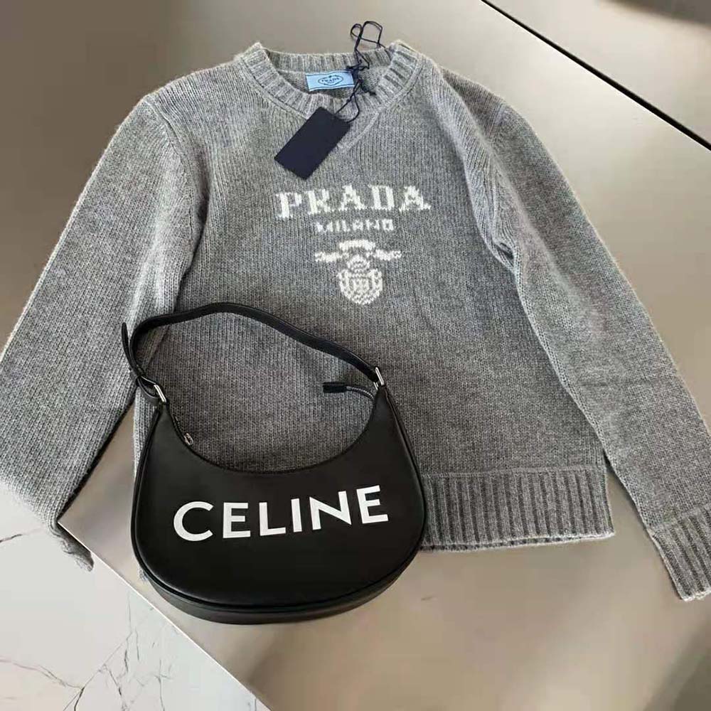 Close-up of silver fabric and Prada logo detail on sweater