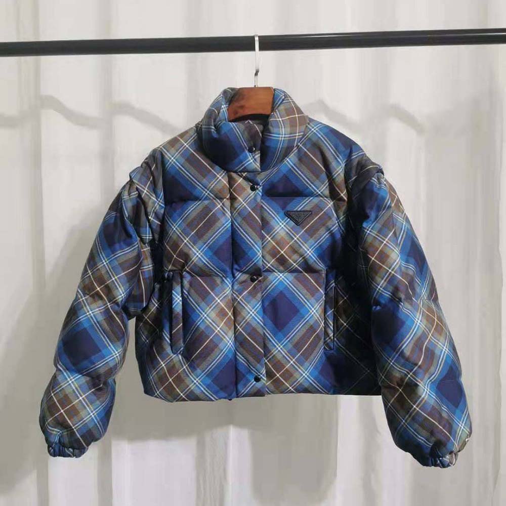Close-up on blue plaid pattern and Prada logo hardware on jacket zipper