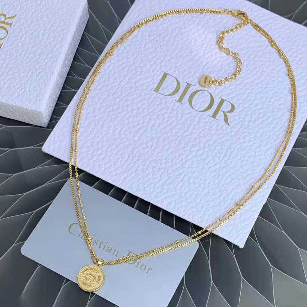 Close-up of gold-tone clasp and ‘30 Montaigne’ charm detail necklace