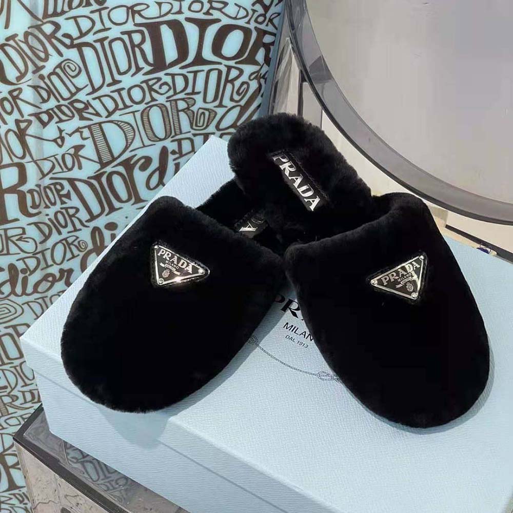 Close-up of Prada enameled triangle logo on black shearling sabots