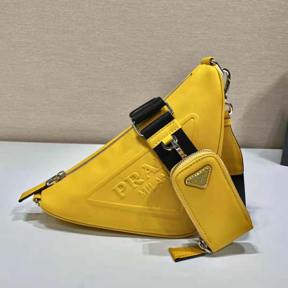 Close-up of silver Prada logo hardware on yellow triangle shoulder bag