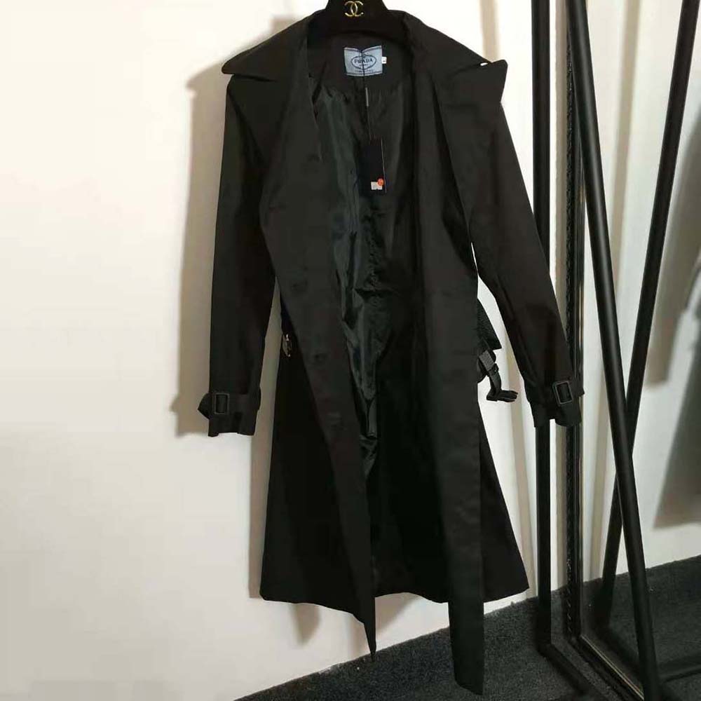 Close-up of signature Prada hardware on black Re-Nylon trench coat