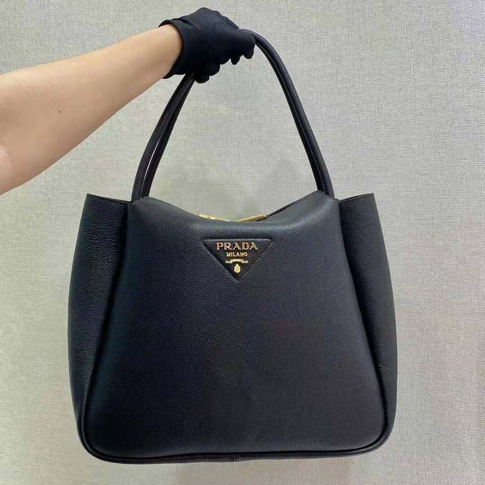 Close-up of Prada metal lettering logo on black leather handbag