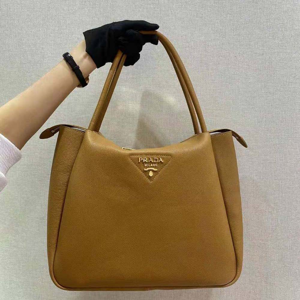 Close-up of Prada metal lettering logo on brown leather handbag