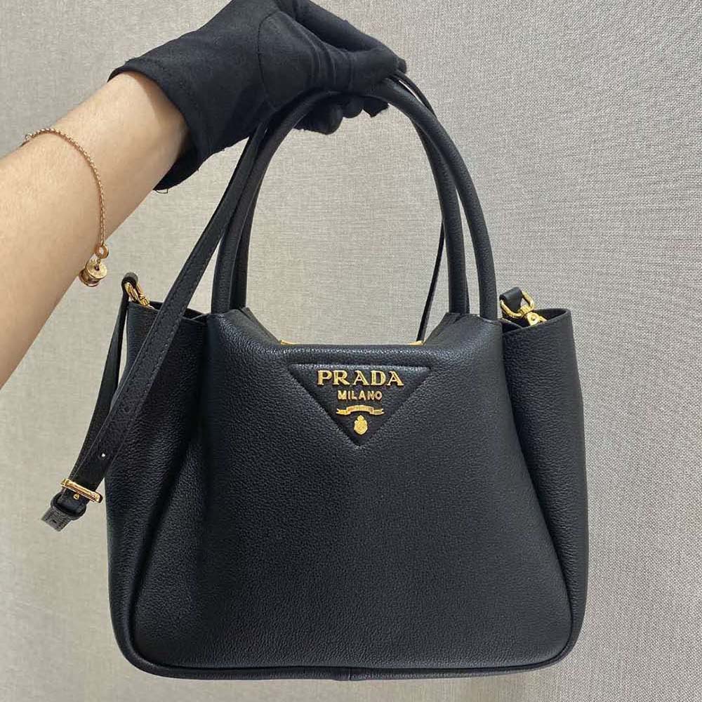 Close-up detail of Prada metal lettering on black leather handbag