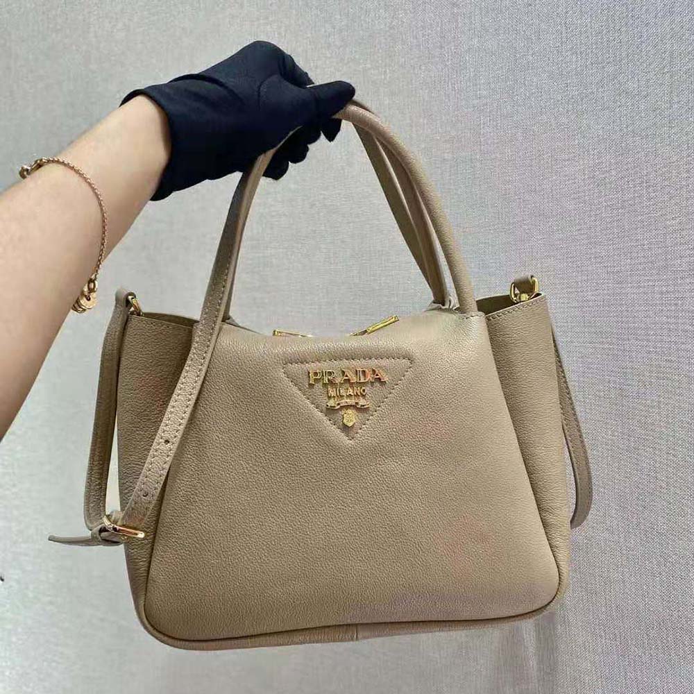 Close-up of Prada metal lettering logo on sandy leather handbag