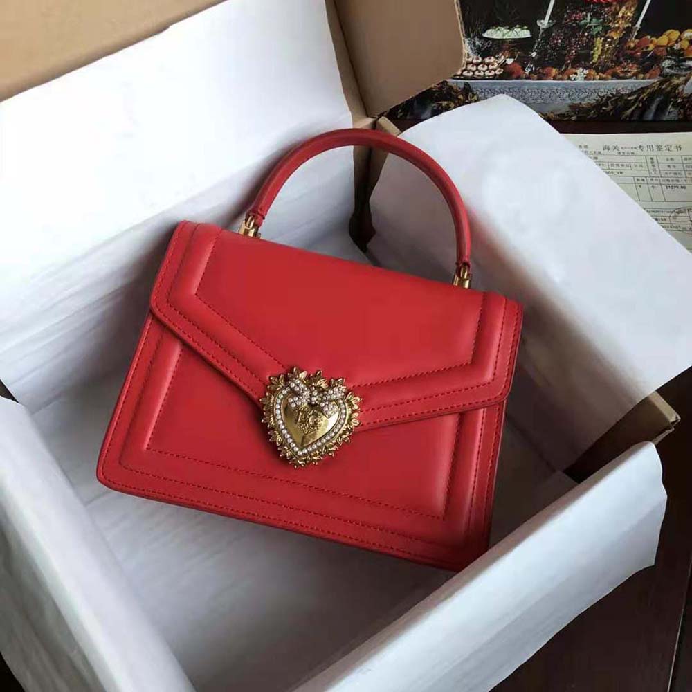 Close-up of gold-tone Devotion heart clasp on red calfskin bag