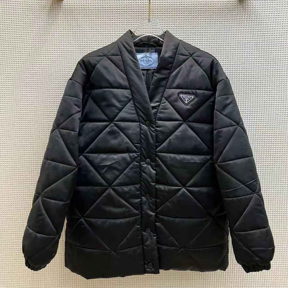 Close-up of Prada triangle emblem hardware on the black quilted jacket