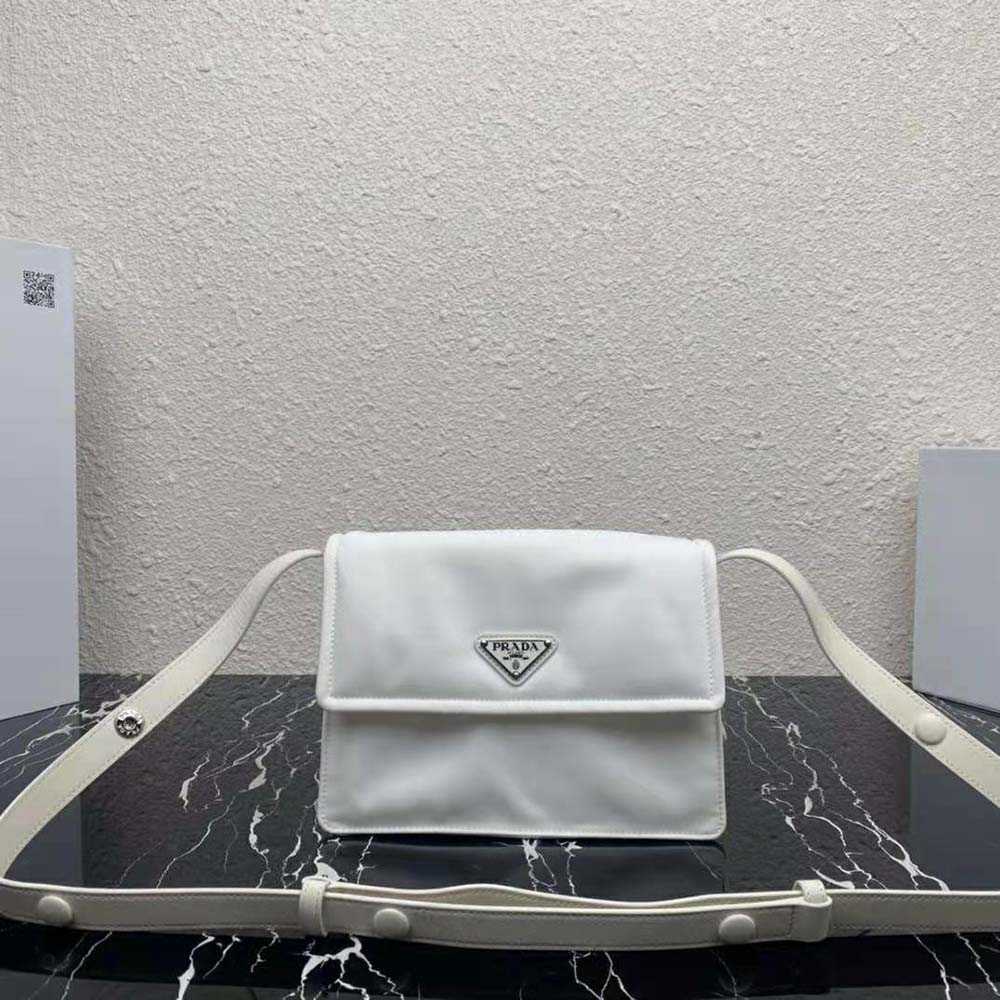 Close-up detail of Prada logo and silver hardware on white shoulder bag