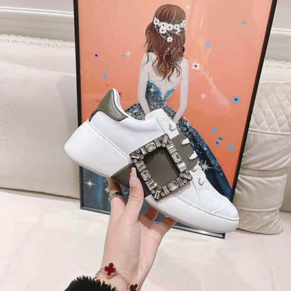 Close-up of sparkling strass buckle on white leather Roger Vivier sneakers