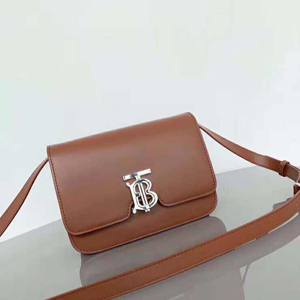 Close-up of gold-tone Thomas Burberry monogram clasp on small leather bag