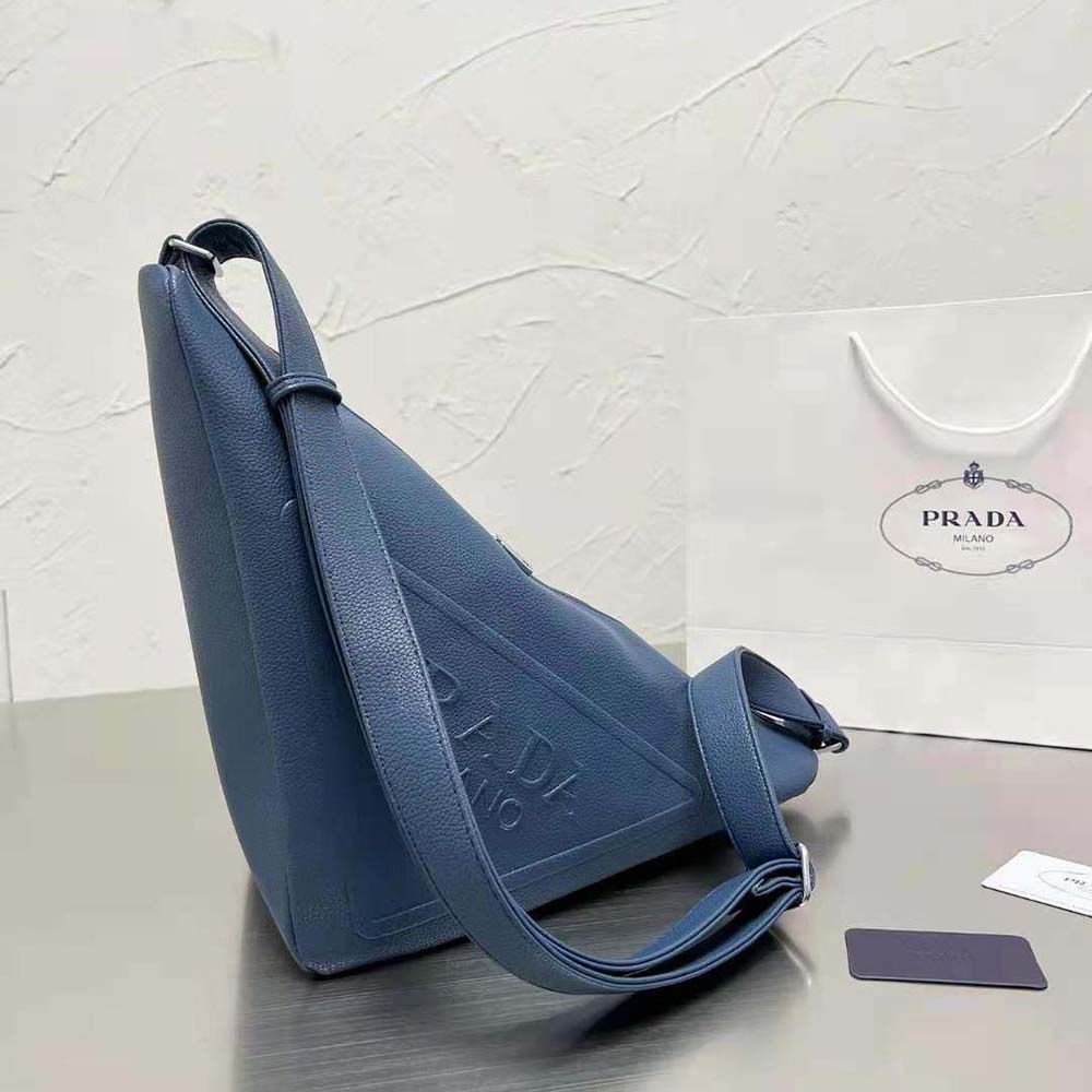 Close-up of silver Prada triangle logo hardware on navy leather bag