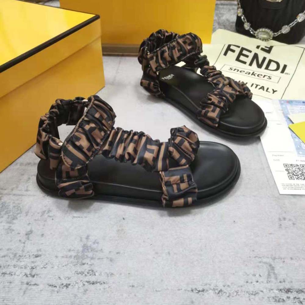 Close-up of gold-tone Fendi logo on the brown satin sandals