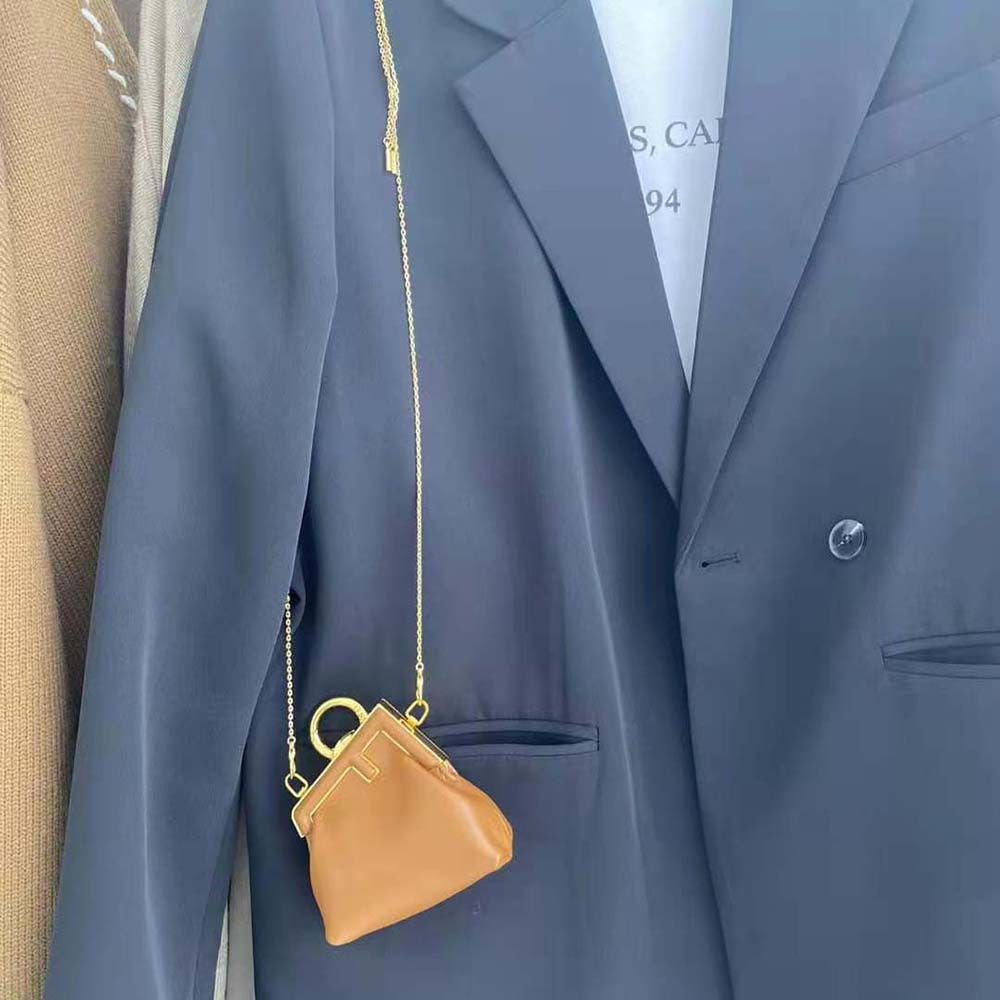Close-up on gold-tone Fendi charm detail on brown leather bag