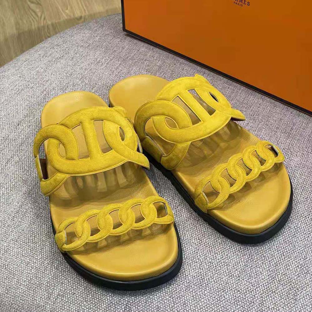 Close-up on signature Hermes hardware on yellow suede sandal strap