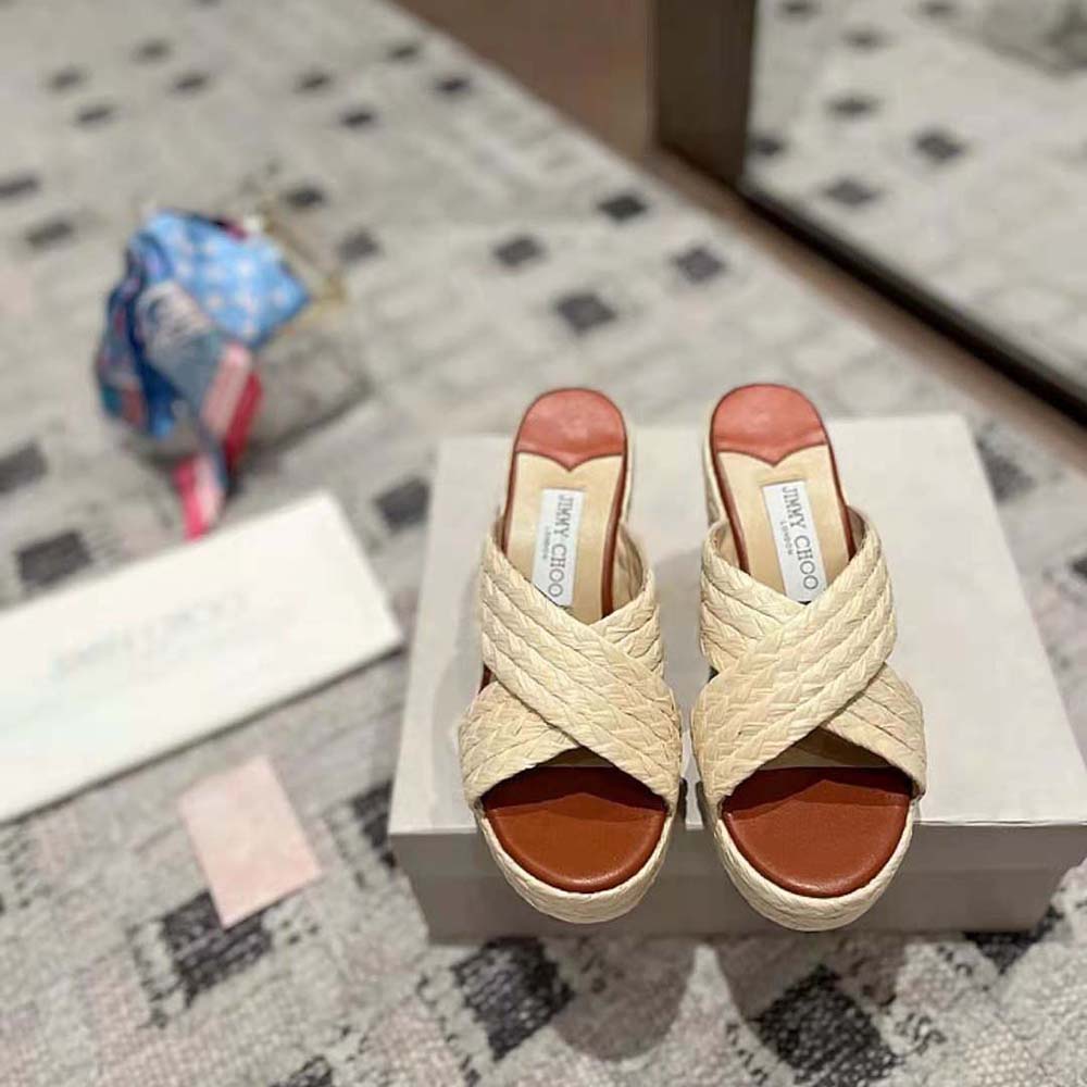 Close-up of gold JC monogram on raffia wedge mules by Jimmy Choo
